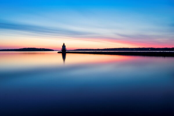 The lighthouse is reflected in the rainbow water