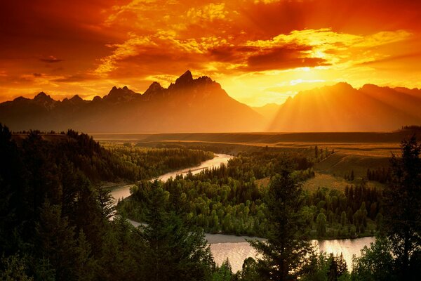 Jasny Zachód słońca nad rzeką w dolinie. Góry na horyzoncie