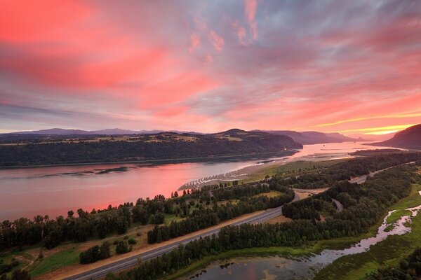 Puesta de sol roja sobre el río y el bosque