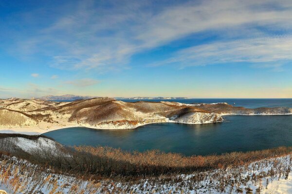 Blue sea on the background of snowy hills