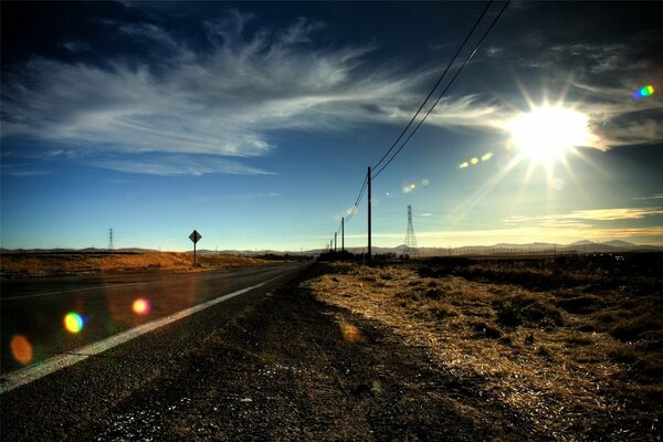 Una strada nella prateria. Sole. Molti pali lungo la strada