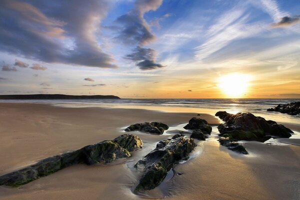 Puesta de sol sobre el mar. playa de arena. rocas. Sol