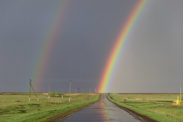 Doppelter Regenbogen. Straße mitten in den Wiesen
