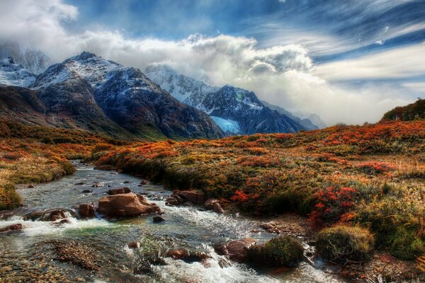 Río de montaña y picos en las nubes