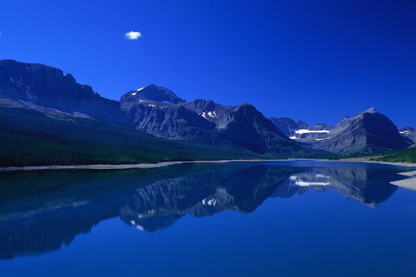 Berge und Gras spiegeln sich im Wasser wider