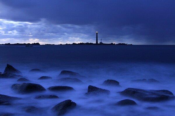 Faro lejano en el mar azul-azul