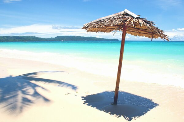 Playa azul con arena blanca y sombrilla