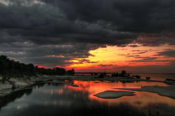 Mysteriöser Sonnenuntergang am Wasser vor dem Sturm