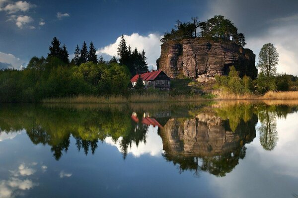 Maison solitaire sous un rocher sur le lac