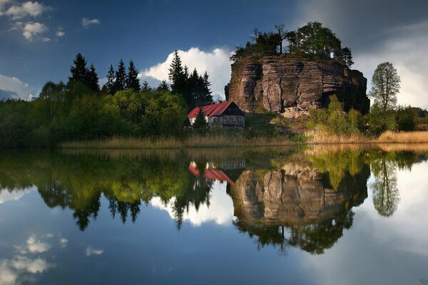 Casa solitaria sotto una roccia su un lago