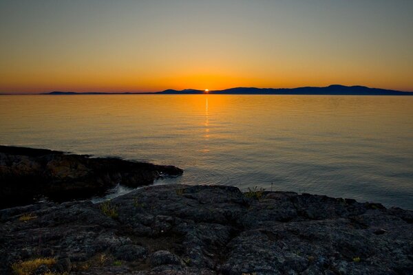 Sunset on the stone shore by the lake