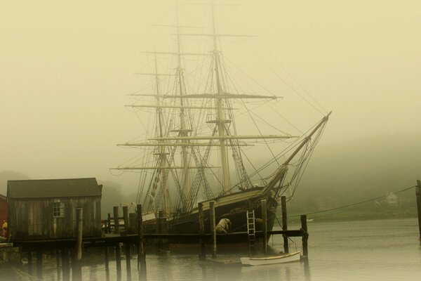 Sailboat in the fog at the wooden pier