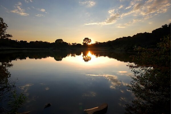 Der Sonnenuntergang erhellt den See und die Bäume sind um ihn herum