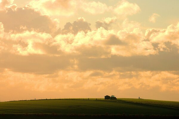 Tractor in the field against the background of clouds