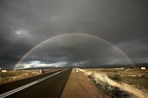 Route qui passe sous l arc-en-ciel sur fond de nuages