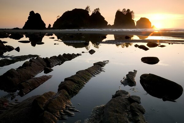 El sol sale de detrás de las rocas sobre el agua