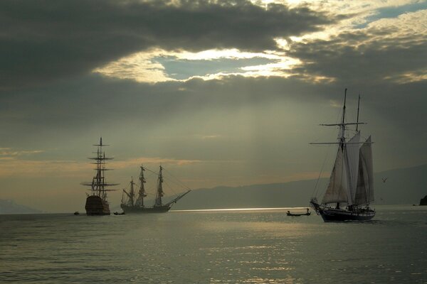 Segelboote und eine Yacht im Meer. Sonnenlicht durch Wolken