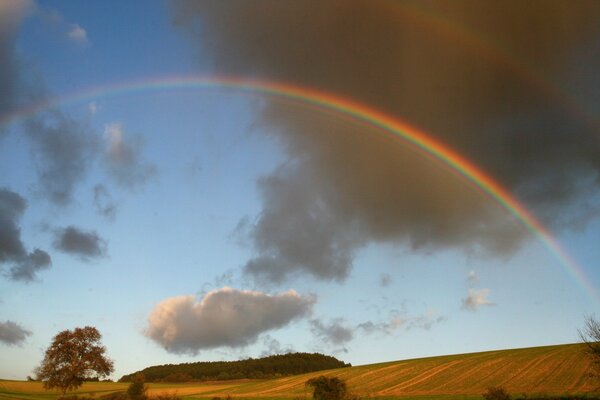 Regenbogen über Feldern und Wäldern und hohen Hügeln