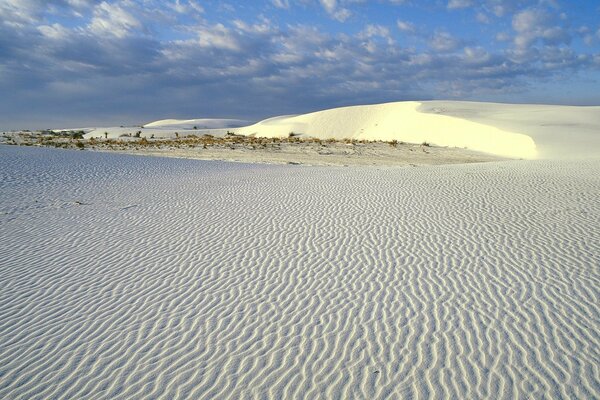 Белый песок пустыни на облачно серо голубом небе