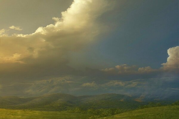 Die Hügel sind grün auf dem Hintergrund der Wolken