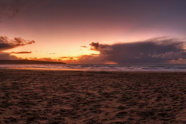 Piaszczysta plaża z zachodem słońca i chmurami