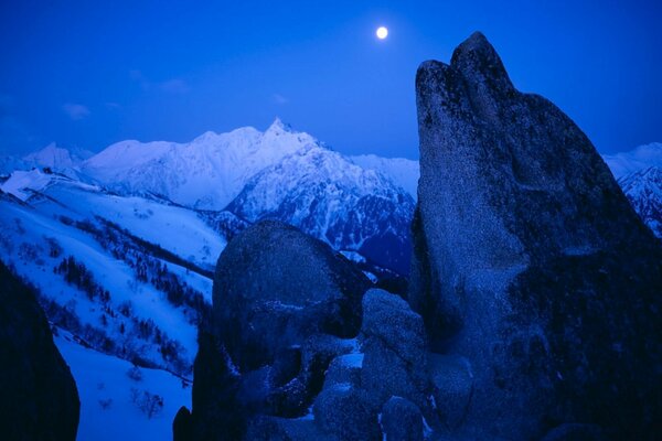 Paysage de nuit des sommets enneigés des montagnes à la lumière de la lune