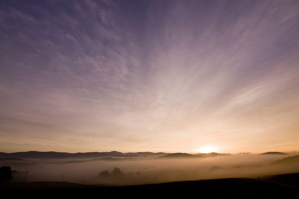 Niebla de la mañana. El sol sale detrás de las colinas