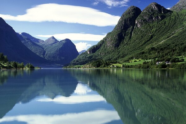 Berge vor dem Hintergrund des blauen Himmels und der weißen Wolken, die sich im Wasser widerspiegeln