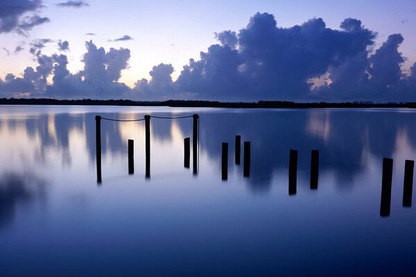 Postes de madera en el río por la noche