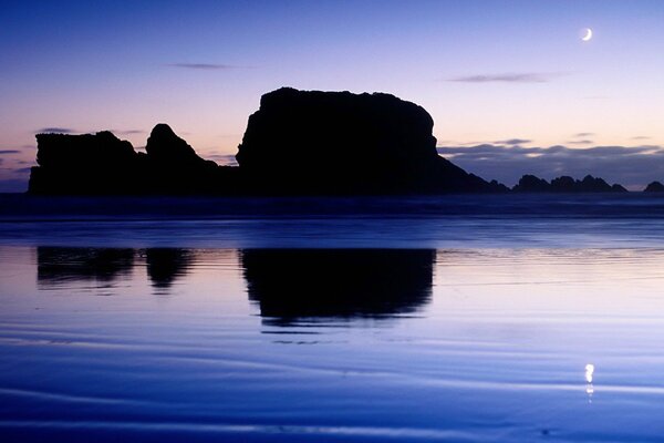 Die Felsen spiegeln sich im Wasser vor dem Hintergrund des Sonnenuntergangs wider