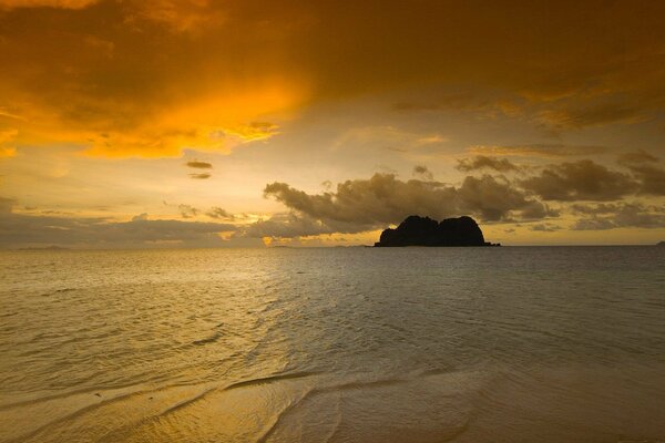 A lonely rock in the sea against the background of the sunrise