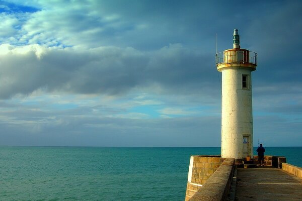 A lonely fisherman at the lighthouse on the sea