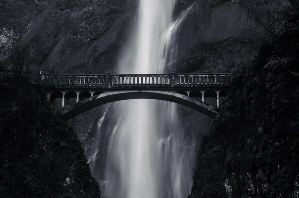 Photo en noir et blanc avec pont et cascade