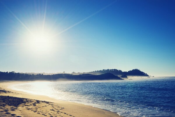 Jasne słońce i ciepłe morze, piaszczysty brzeg ze śladami stóp