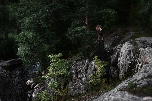 Mädchen auf Steinen auf einem Hintergrund von Bäumen