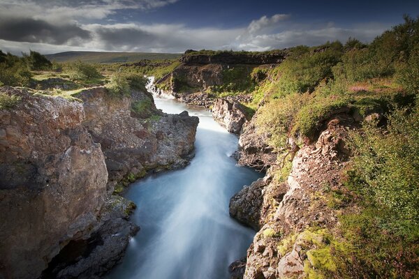 Ein Fluss zwischen Felsen und Wolken