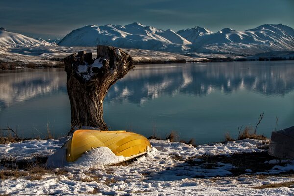 Yellow boat on the shore of the lake. Mountains on the horizon