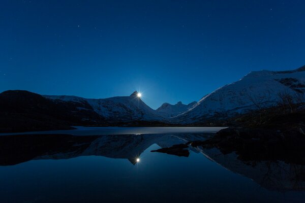 Paesaggio notturno invernale di un lago innevato di montagna