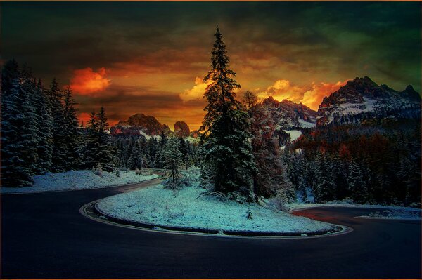 The road on the background of sunset in the snowy mountains