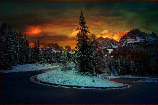 Camino en el fondo de la puesta de sol en las montañas nevadas