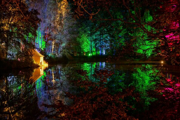Bunte Lichter werden im Teich reflektiert. Haus am Ufer des Teiches