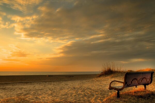A bench on the beach at sunset