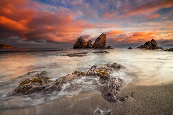 En una playa en Italia hay piedras, rocas visibles. Las nubes en el cielo son muy hermosas