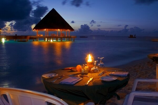 Romantisches Abendessen am Strand am Abend vor dem Hintergrund des Ozeans zu sehen