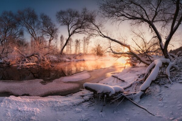 Coucher de soleil et rivière gelée dans la neige