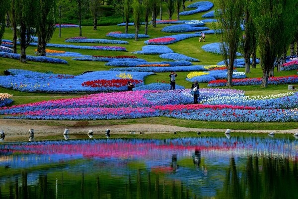 Japanischer Park mit einem transparenten Teich und hellen Blumenbeeten in ungewöhnlicher Form