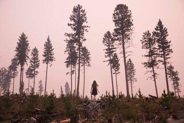 The girl is standing in the middle of the forest