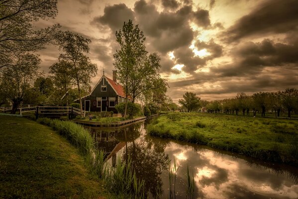 Haus mit See und Grün unter Dämmerwolken