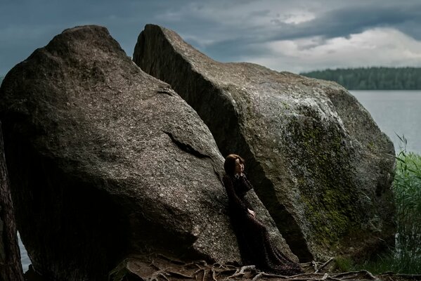 Beautiful girl on the background of a huge stone