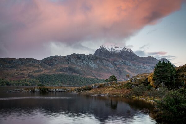 Thunderclouds on the background of snowy mountains lakes and autumn trees